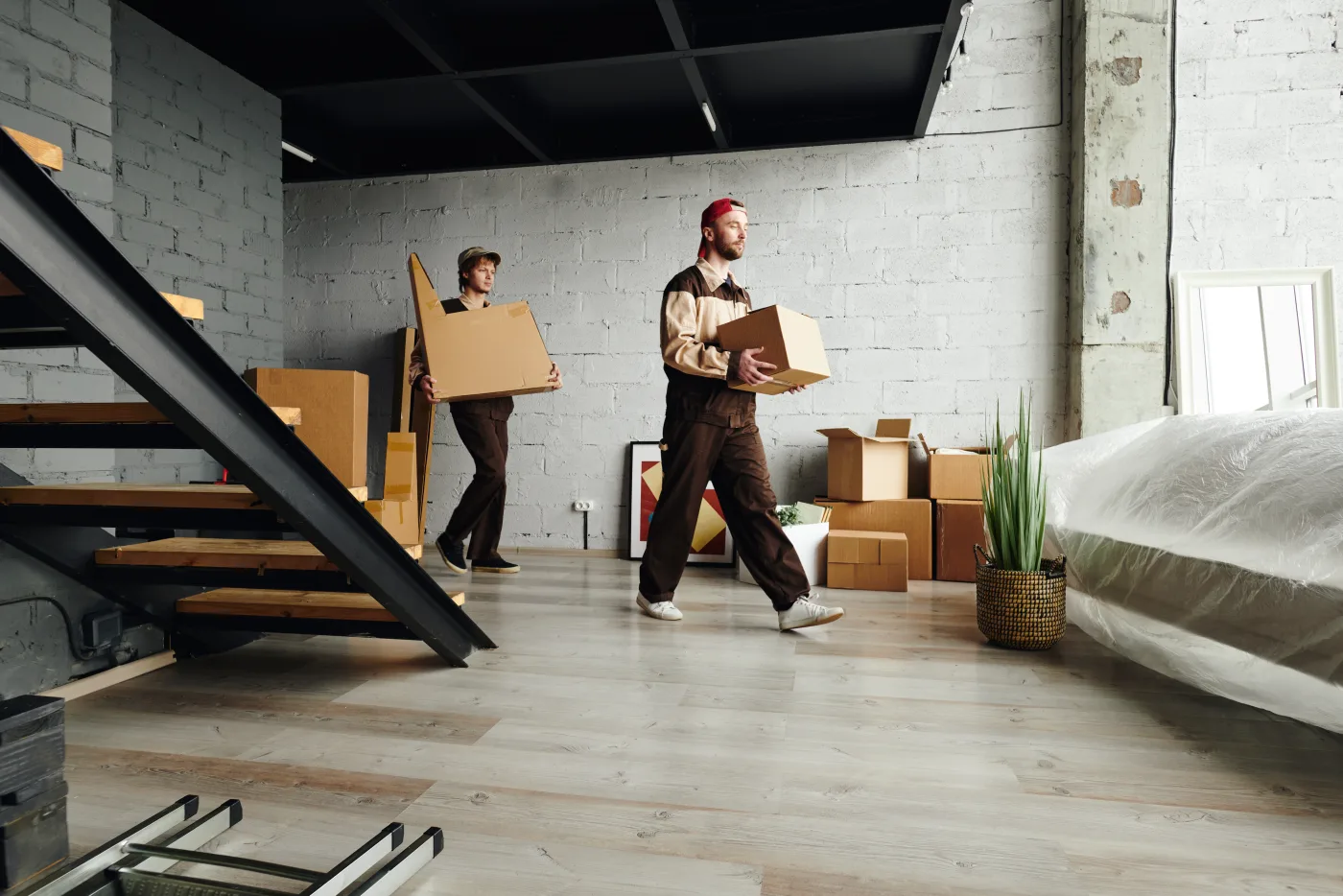 Two movers in workwear carrying labelled boxes into an apartment